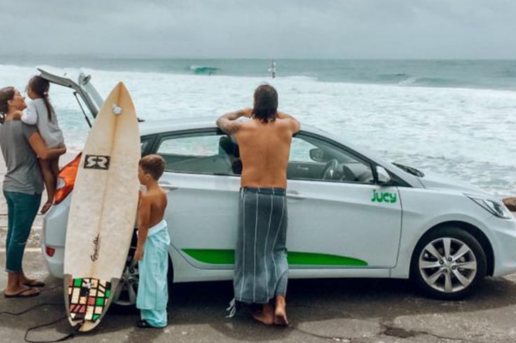 family stands by jucy car in byron bay australia