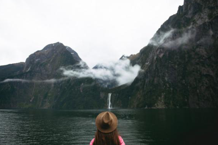 Women in hat standing by lake